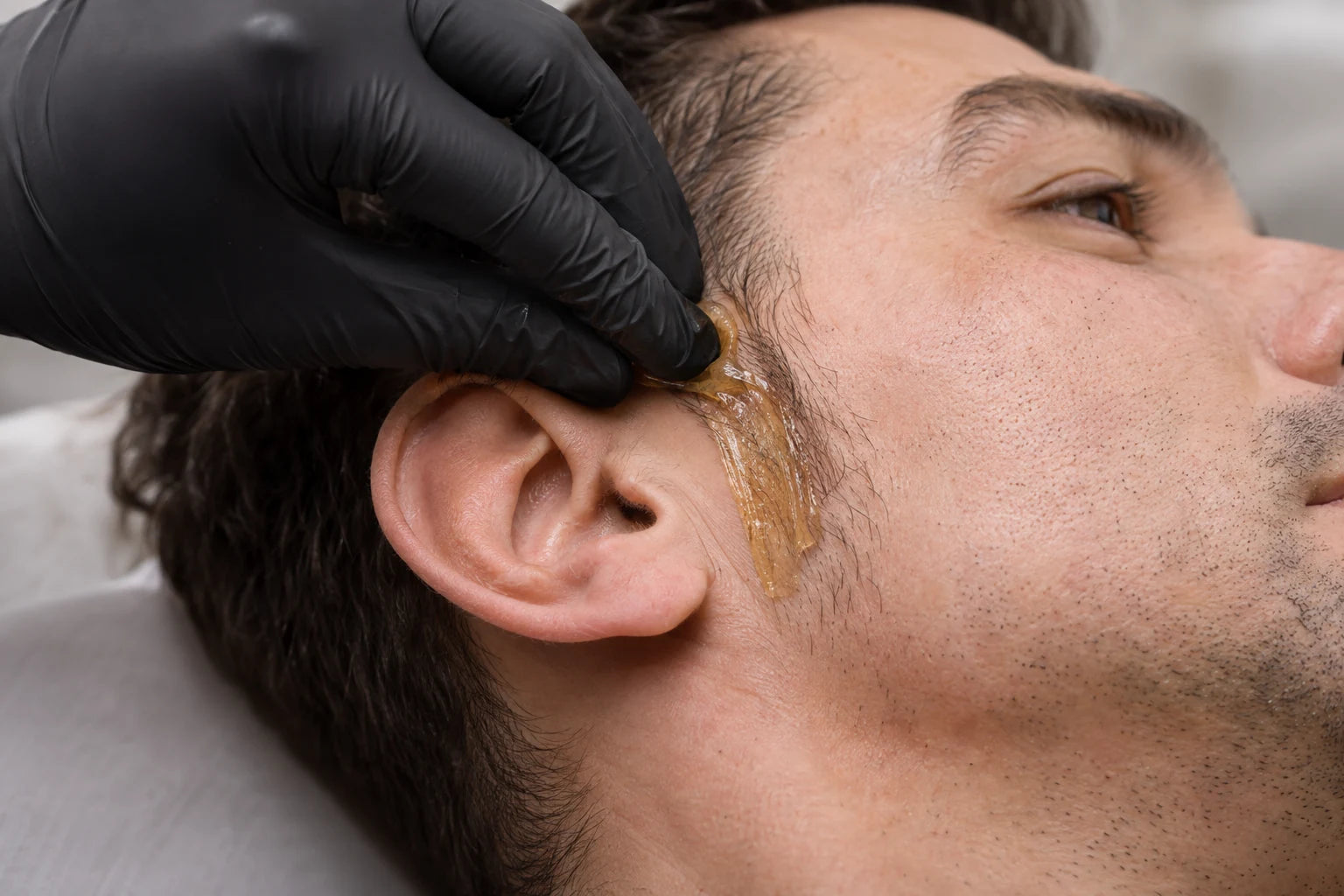 Illustrative close-up of sugar paste application at a man’s sideburn